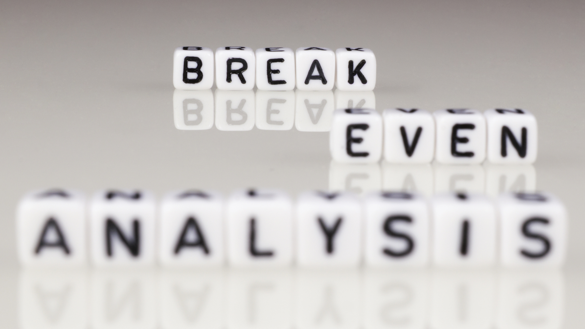 Close-up of dice spelling 'Break Even Analysis,' symbolizing financial clarity and decision-making through accurate break-even calculations.