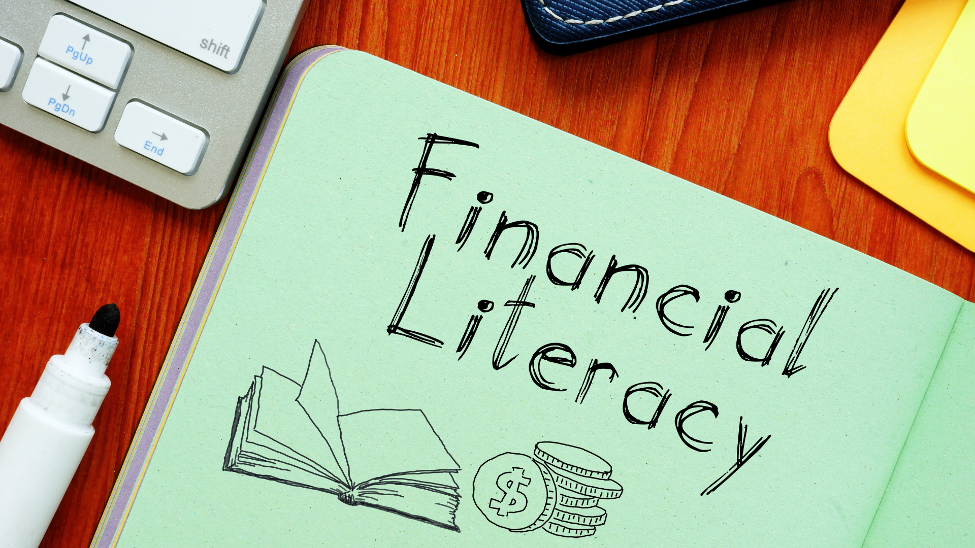 A light green notebook with 'Financial Literacy' written in bold, accompanied by hand-drawn illustrations of an open book and stacked coins, placed on a wooden desk next to office supplies, representing Financial Literacy Training for Entrepreneurs focused on mastering essential business financial skills.