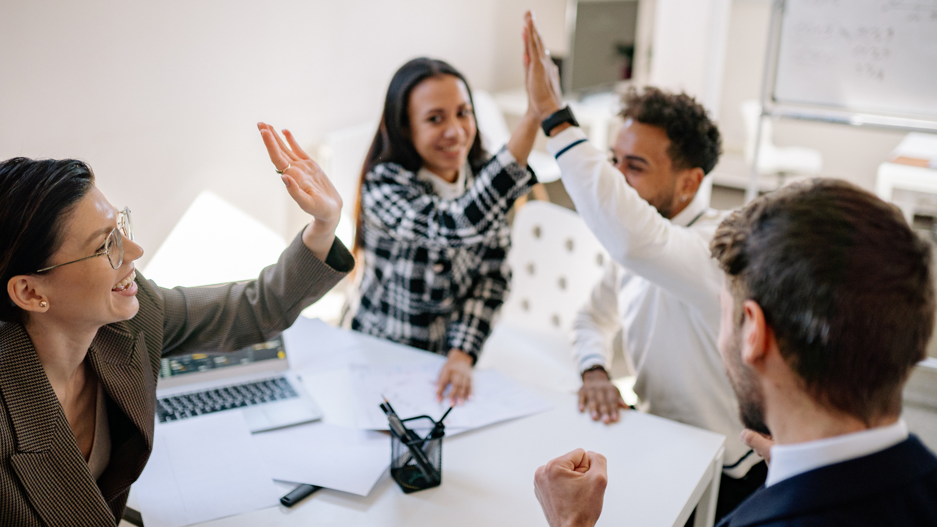 Team celebrating a high-five in an office setting, symbolizing success achieved through Strategic Growth Accountability Services and effective progress tracking.