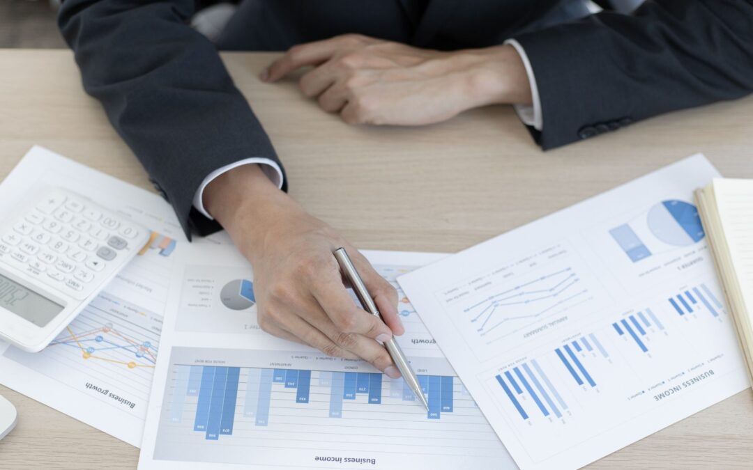 Businessperson analyzing income reports and growth charts with calculator and graphs on desk