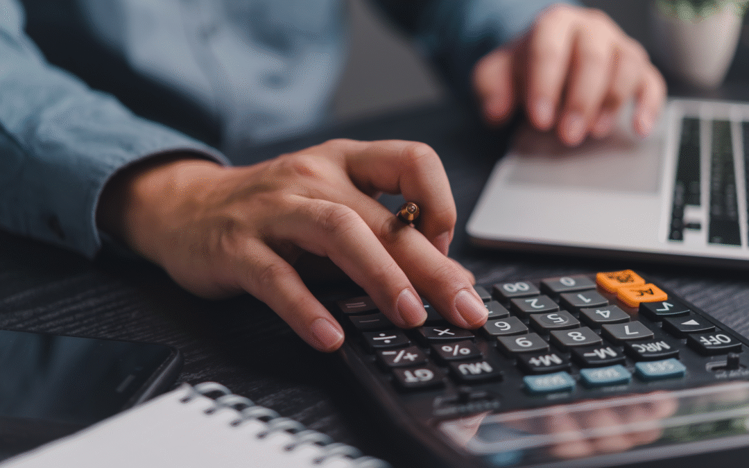 Business owner working with a calculator and laptop, representing outdated bookkeeping methods being replaced with modern digital solutions.