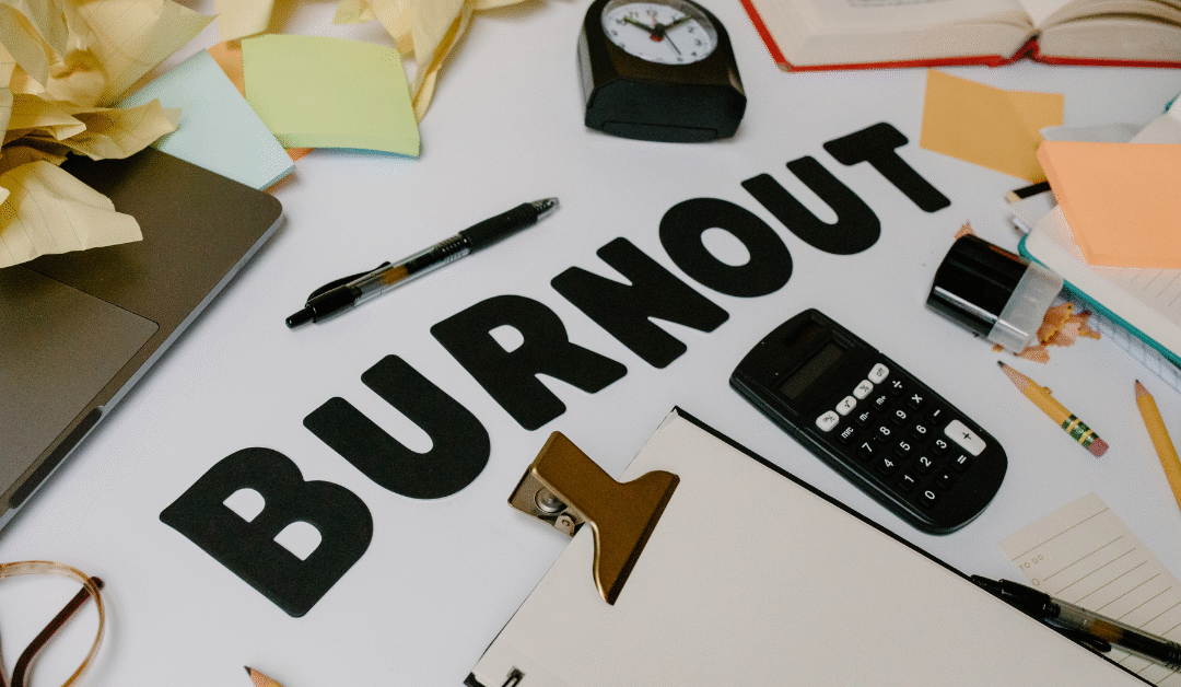 Work desk cluttered with papers, calculator, and clock symbolizing business burnout and stress while growing a company.